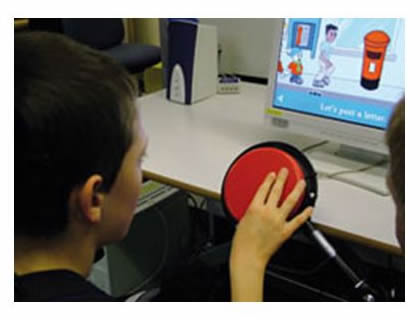 Menino utilizando um acionador de mouse em frente ao computador